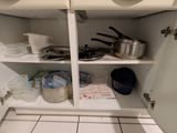 des placards sur lesquels sont posés des casseroles et des poêles, dans une cuisine