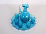 un pichet en verre bleu et des verres posés sur une assiette