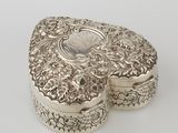 an antique silver box with a floral design on the lid