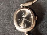 a silver watch that is on a black cloth