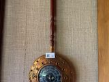 une horloge accrochée au mur, munie d'une poignée en bois