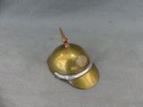 a small gold helmet with a metal handle on a gray surface