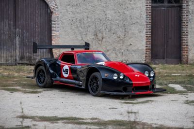 une voiture de course rouge et noire garée devant un immeuble
