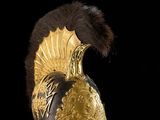 une image représentant un casque doré orné de plumes sur fond noir