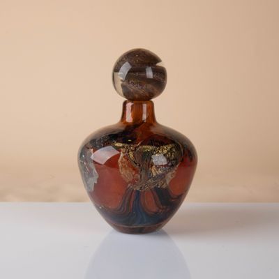 a brown and black vase sitting on a white table