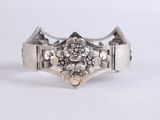 a close up of a silver bracelet with flowers on it