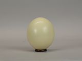 a white egg sitting on top of a wooden stand