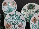 many plates with flowers painted on them on a table