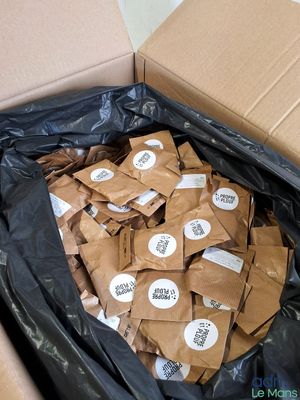 une boîte remplie de sacs en papier kraft sur lesquels sont collés des autocollants