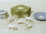 une boîte verte avec des chevaux blancs et une assiette sur laquelle est posée une assiette bleue