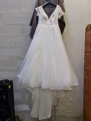 wedding dress hanging on a hanger in front of a brick wall