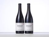 two bottles of red wine sitting next to each other on a table