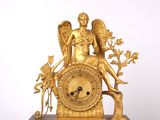 a gold clock with an angel sitting on top of it