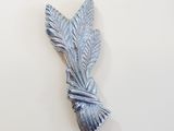 a silver leaf brooch on a white wall