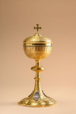 a golden cup with a cross on top sitting on a table