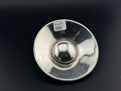une image représentant une assiette en argent posée sur une surface noire