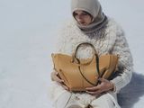 a woman sitting in the snow holding a purse
