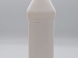 a white bottle of liquid sitting on a white surface