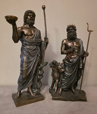 deux statues représentant un homme et une femme accompagnés d'un chien, posées sur une table