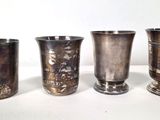 four silver vases sitting on a table next to each other