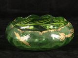 a green glass bowl with birds on it on a black background