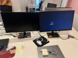 two computer monitors sitting on a desk next to each other