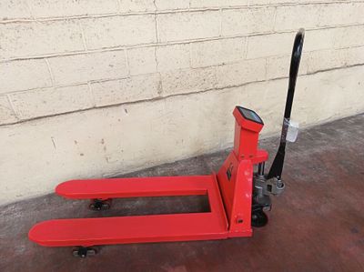 un chariot élévateur rouge posé par terre à côté d'un mur de briques