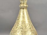 a gold vase sitting on a table with a gray background
