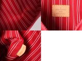 the inside of a red bag with white stripes and a wooden handle