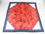 a close up of a red and blue square scarf on a table