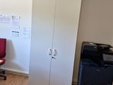 une pièce équipée d'un bureau, d'une chaise, d'une imprimante et d'une armoire