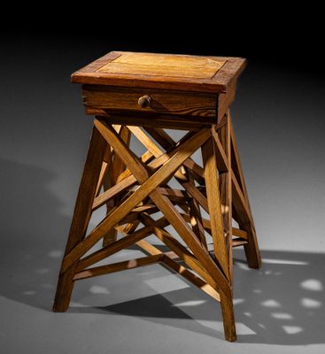 a wooden stool with a drawer on top of it in a dark room