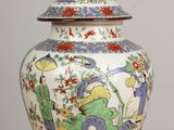 a vase with a lid on a table with a lamp on it