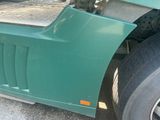 a close up of a green truck with a flat tire