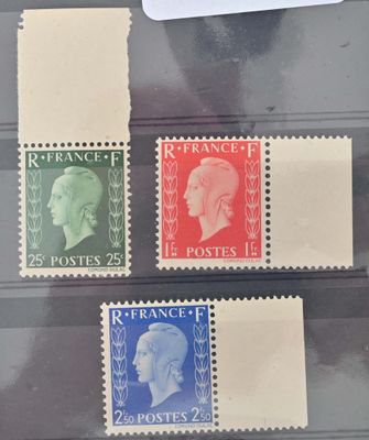 quatre timbres différents exposés dans une vitrine posée sur une table