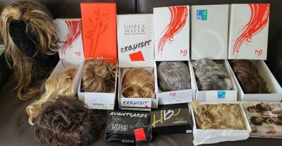 many different types of wigs in a box on a couch
