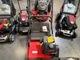 Plusieurs tondeuses à gazon sont alignées en rang dans un garage