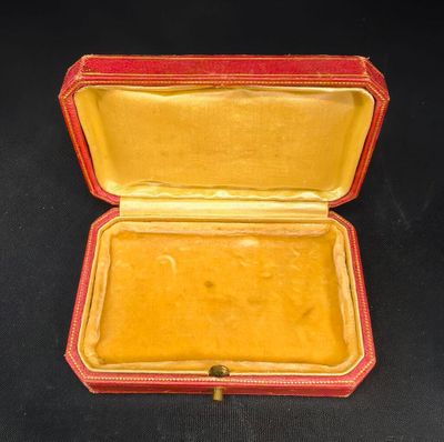 un étui rouge et jaune avec une poignée dorée sur un fond noir