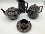 three teapots and a cup on a table