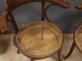 two wooden chairs with wicker seats sit on a wooden floor