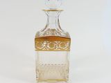 a clear glass bottle with a gold top on a white surface