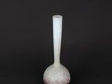 un vase blanc posé sur une surface noire