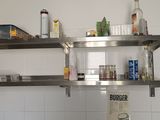 une étagère métallique sur laquelle sont posées des bouteilles, dans une cuisine