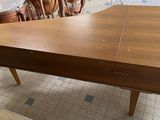 a wooden table with a drawer on it in the middle of a room