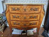 une commode en bois dans une pièce dont l'un des murs est tapissé