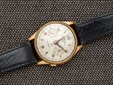 un gros plan d'une montre en or avec un bracelet en cuir noir