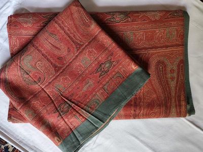 a red and green scarf laying on a bed