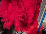 une robe à plumes rouges suspendue à un portant dans un magasin