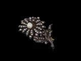 un gros plan d'une broche ornée de perles et de diamants