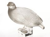 un oiseau en verre posé sur un bloc de verre